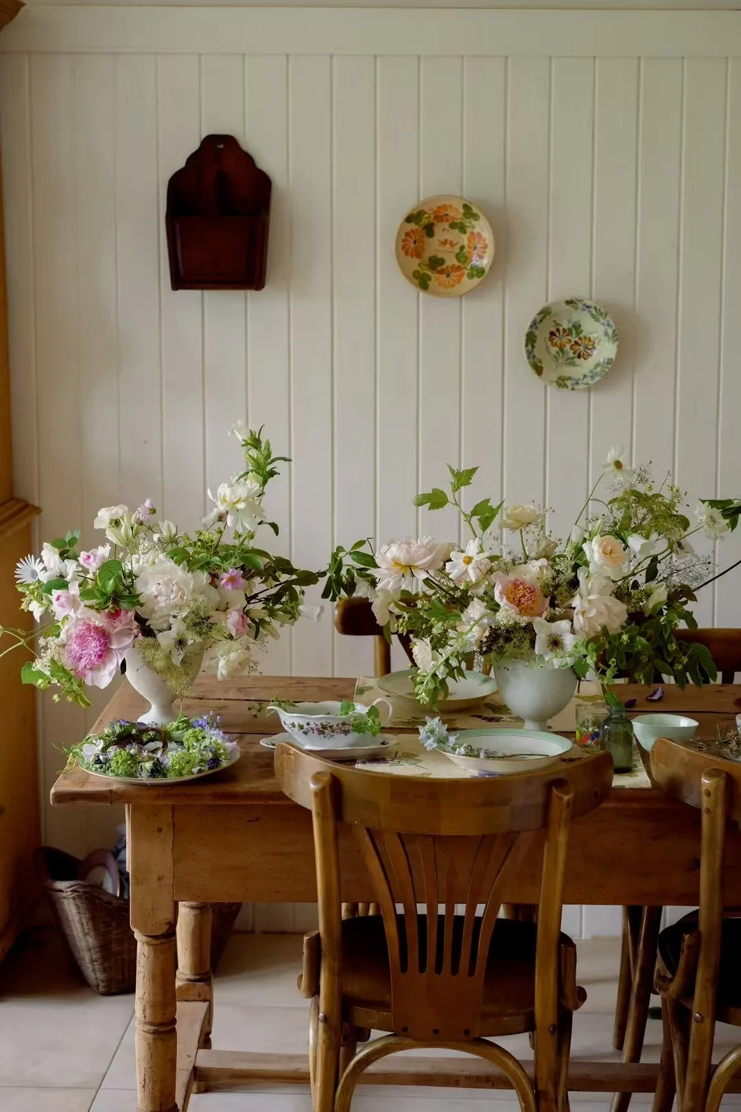 Pastel floral centerpieces on a rustic wooden dining table in a cottage interior