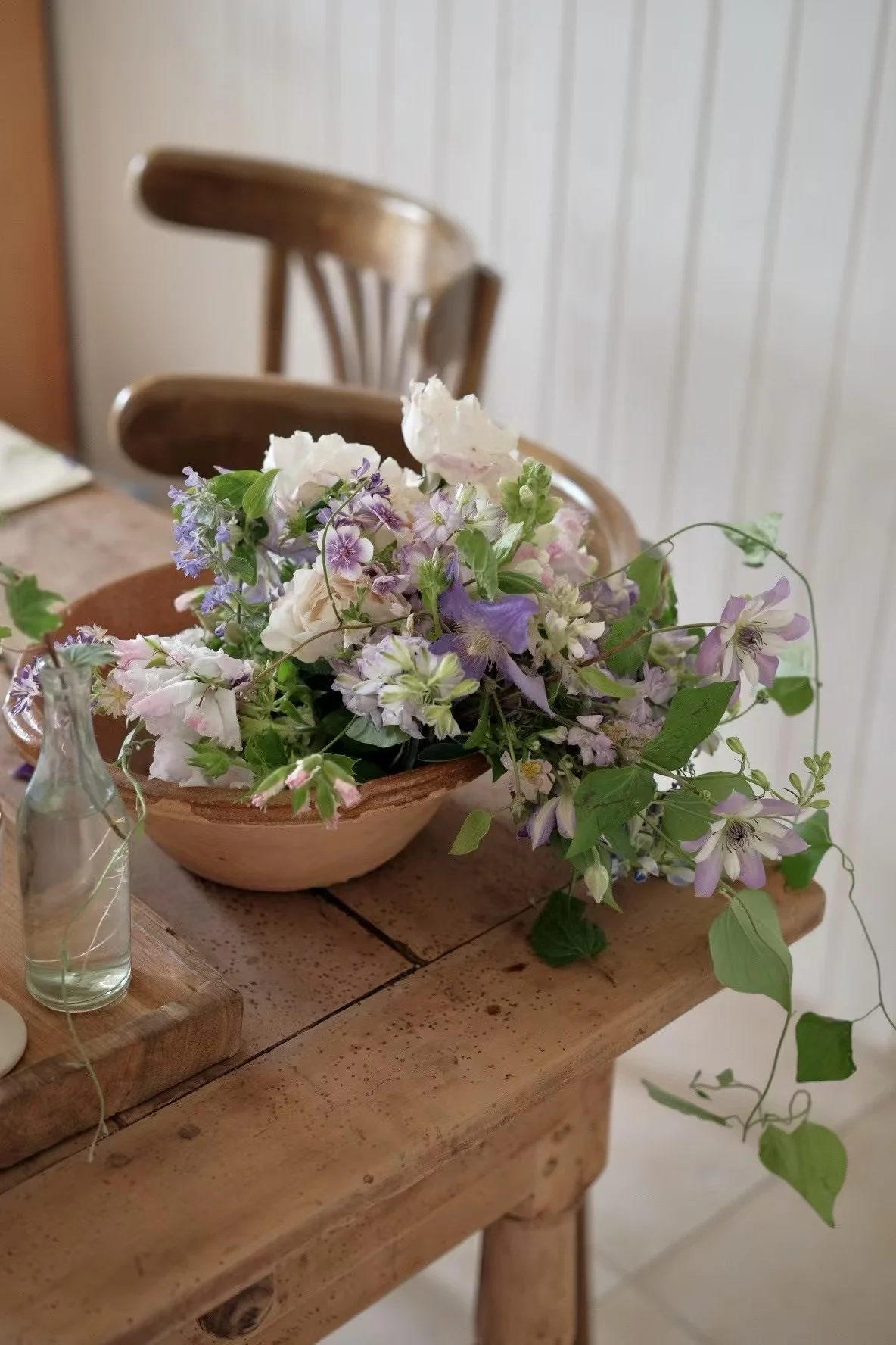 Loose lavender and white floral arrangement with trailing greenery in a terracotta bowl