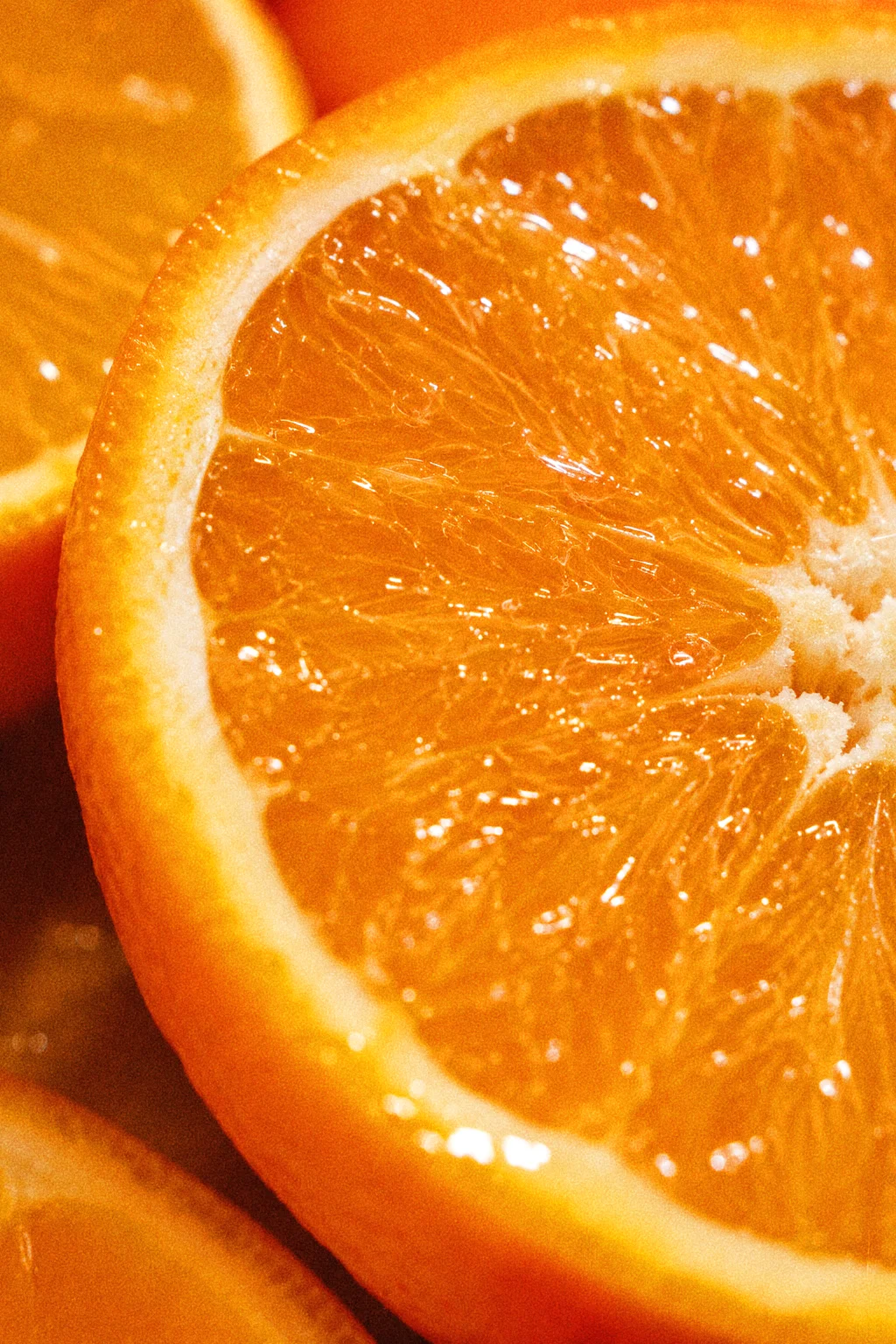 Macro view of overlapping orange slices showing their translucent flesh and textured peel