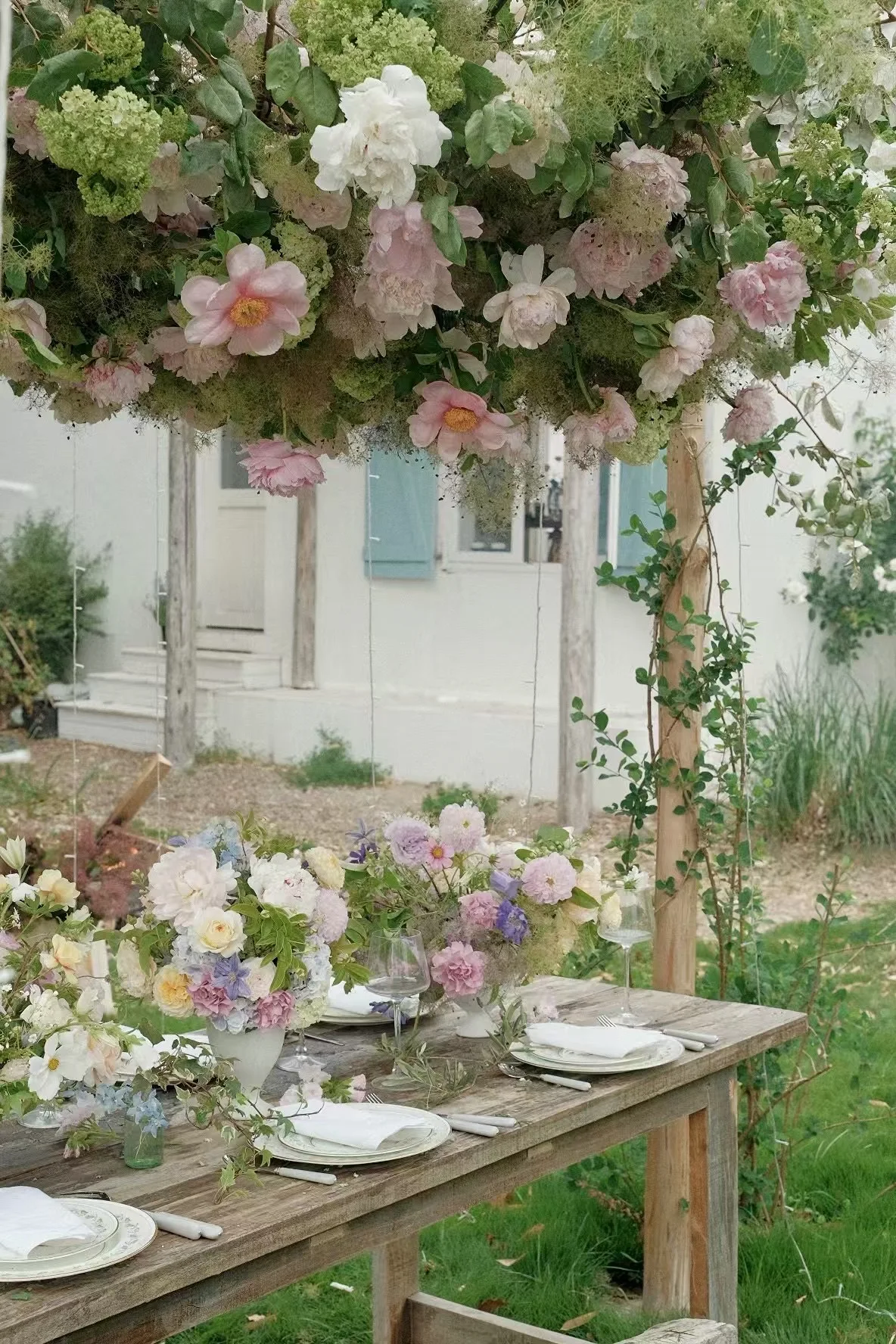 Al fresco reception table beneath a hanging peony cloud in a garden courtyard