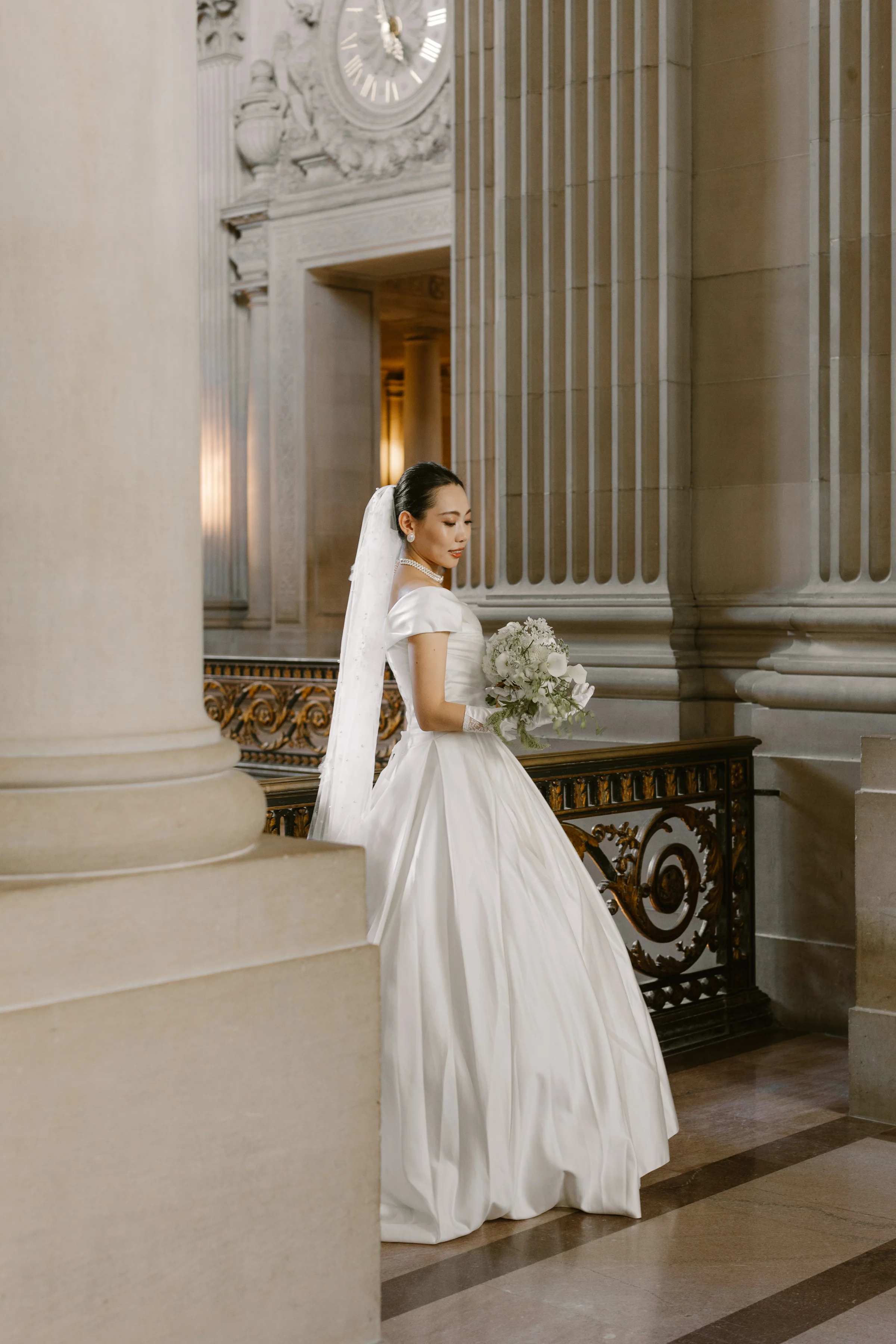 Bride beside a fluted marble column holding her bouquet