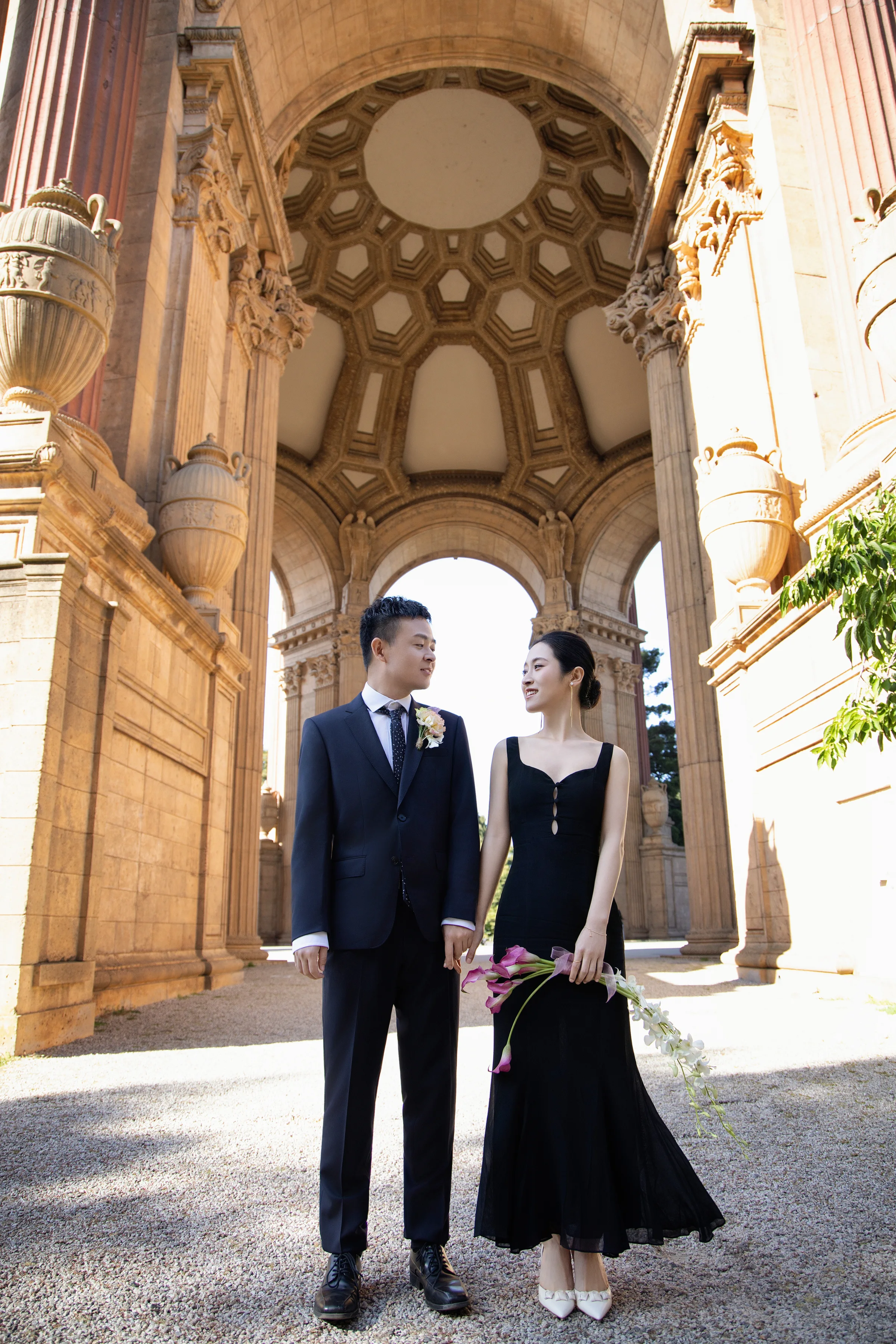 Couple standing under the ornate Palace of Fine Arts rotunda, the bride in a black gown