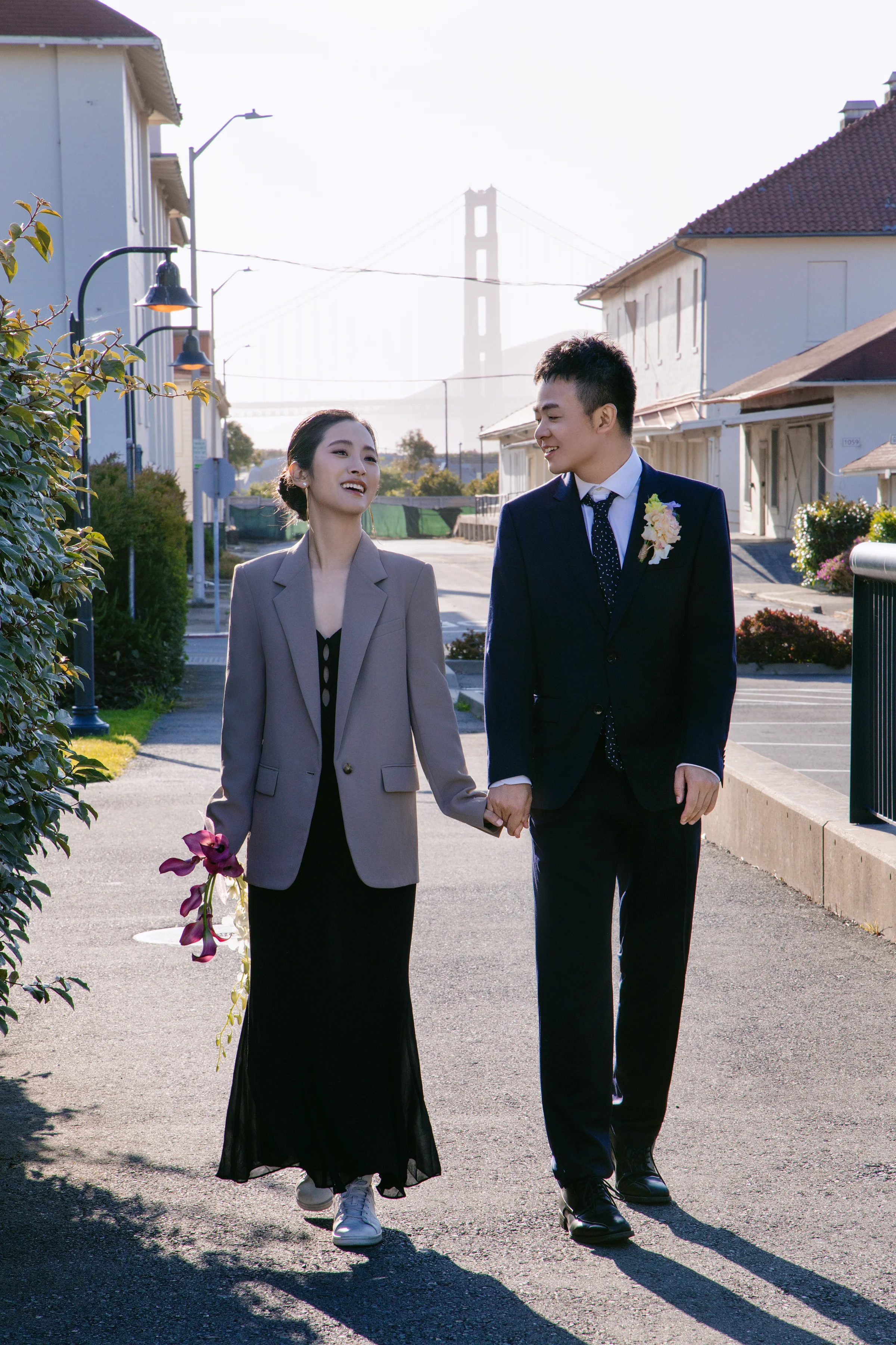 Couple gazing at each other by a column, the bride holding a pink orchid stem