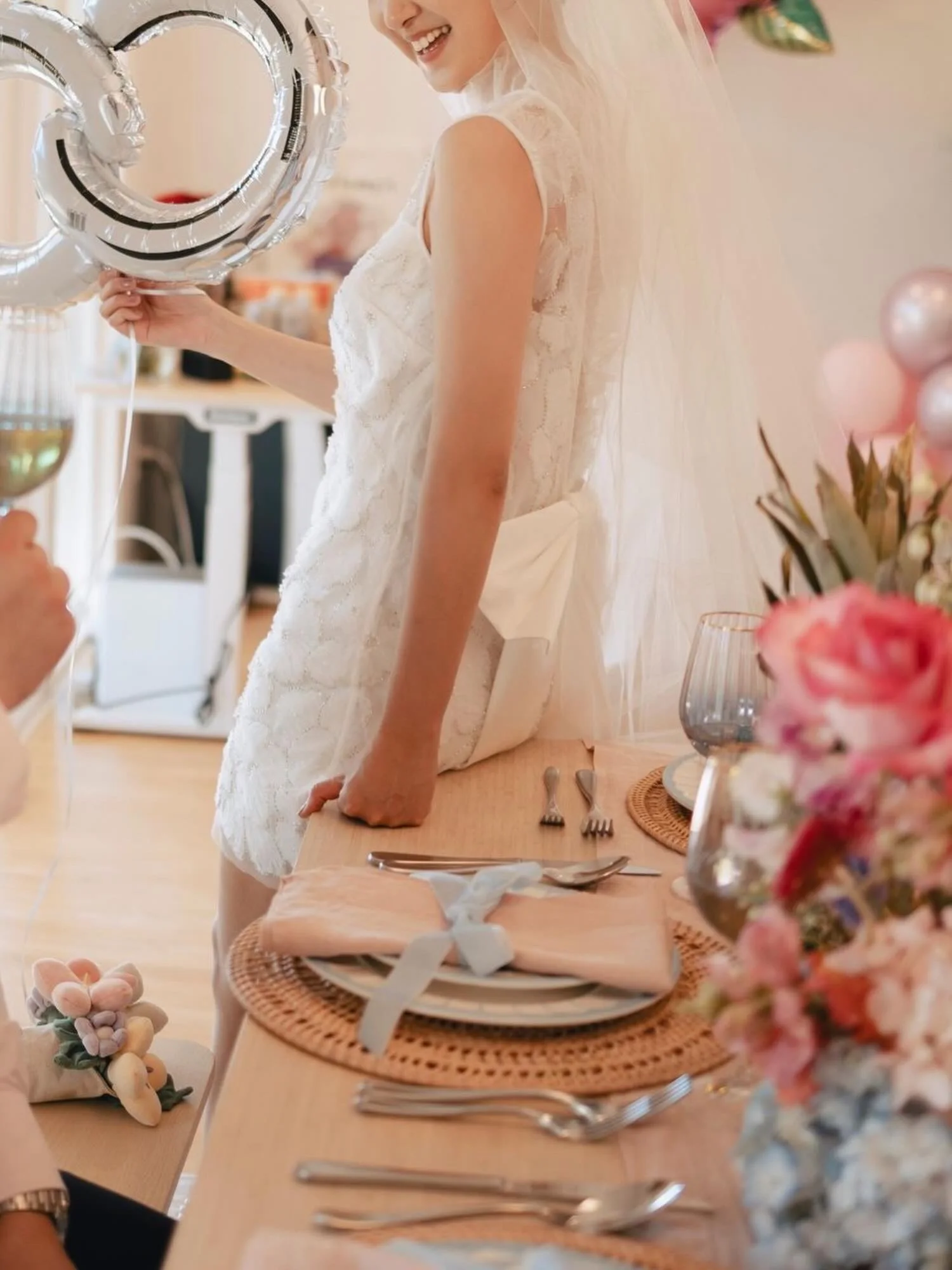 Bride beside the styled reception table, a pink rose and blue hydrangea centerpiece in the foreground