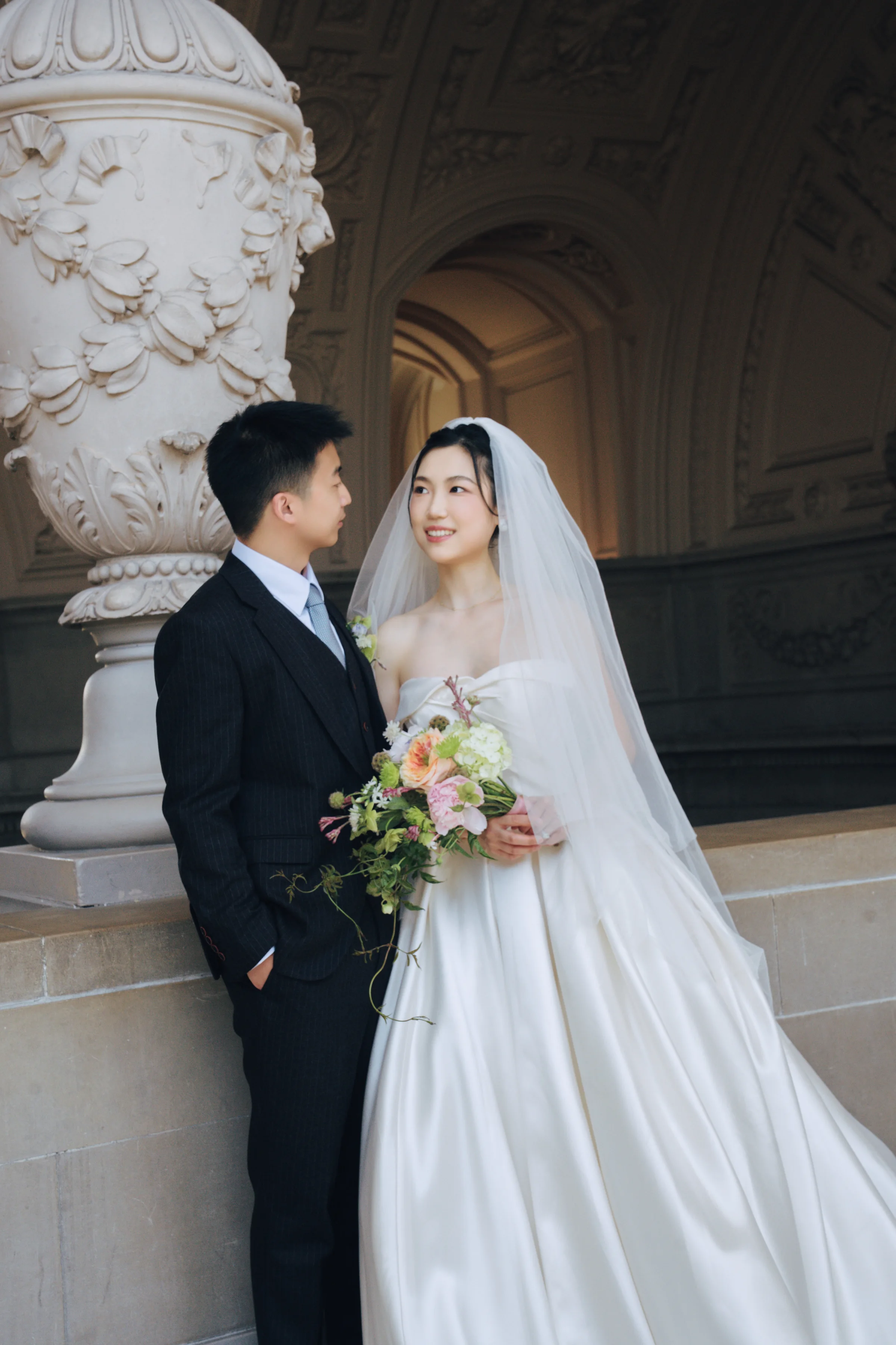 Couple standing together beside a marble pillar