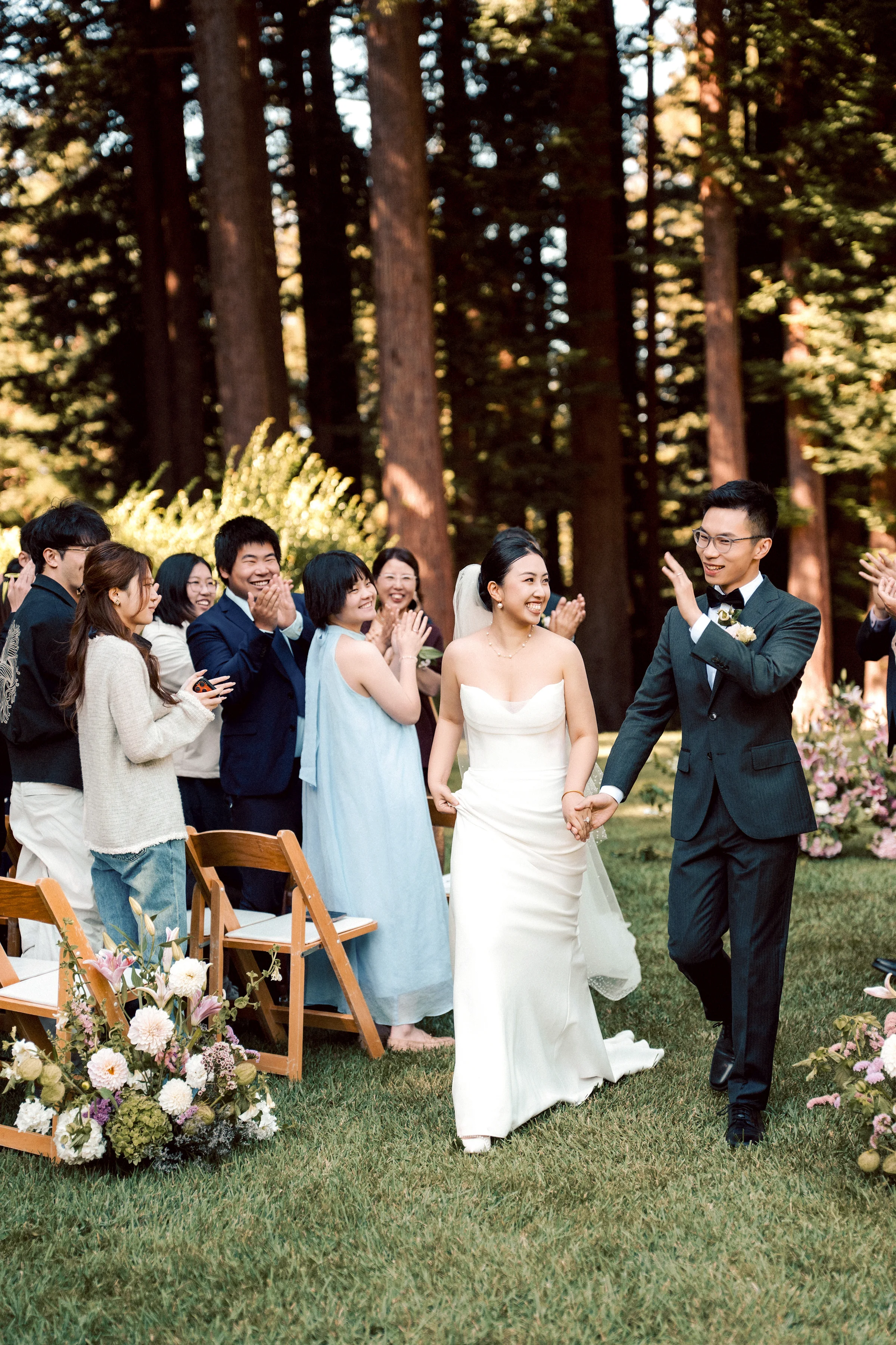 Couple recessing through seated guests in a redwood grove, the bride in a slip gown