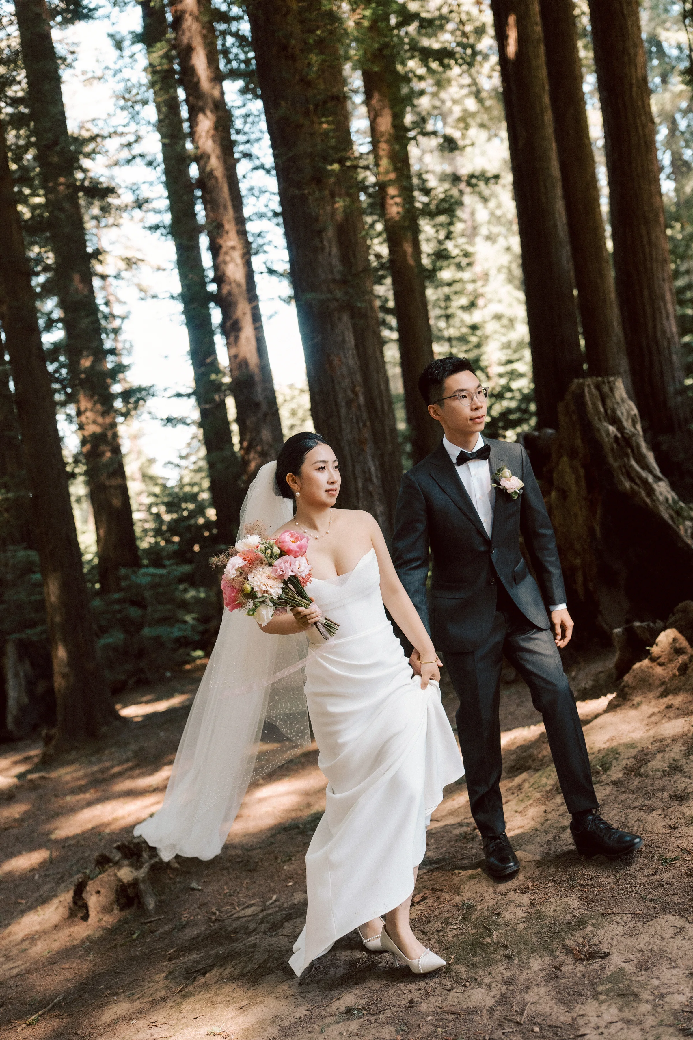 Bride walking toward the groom in a sunlit redwood clearing