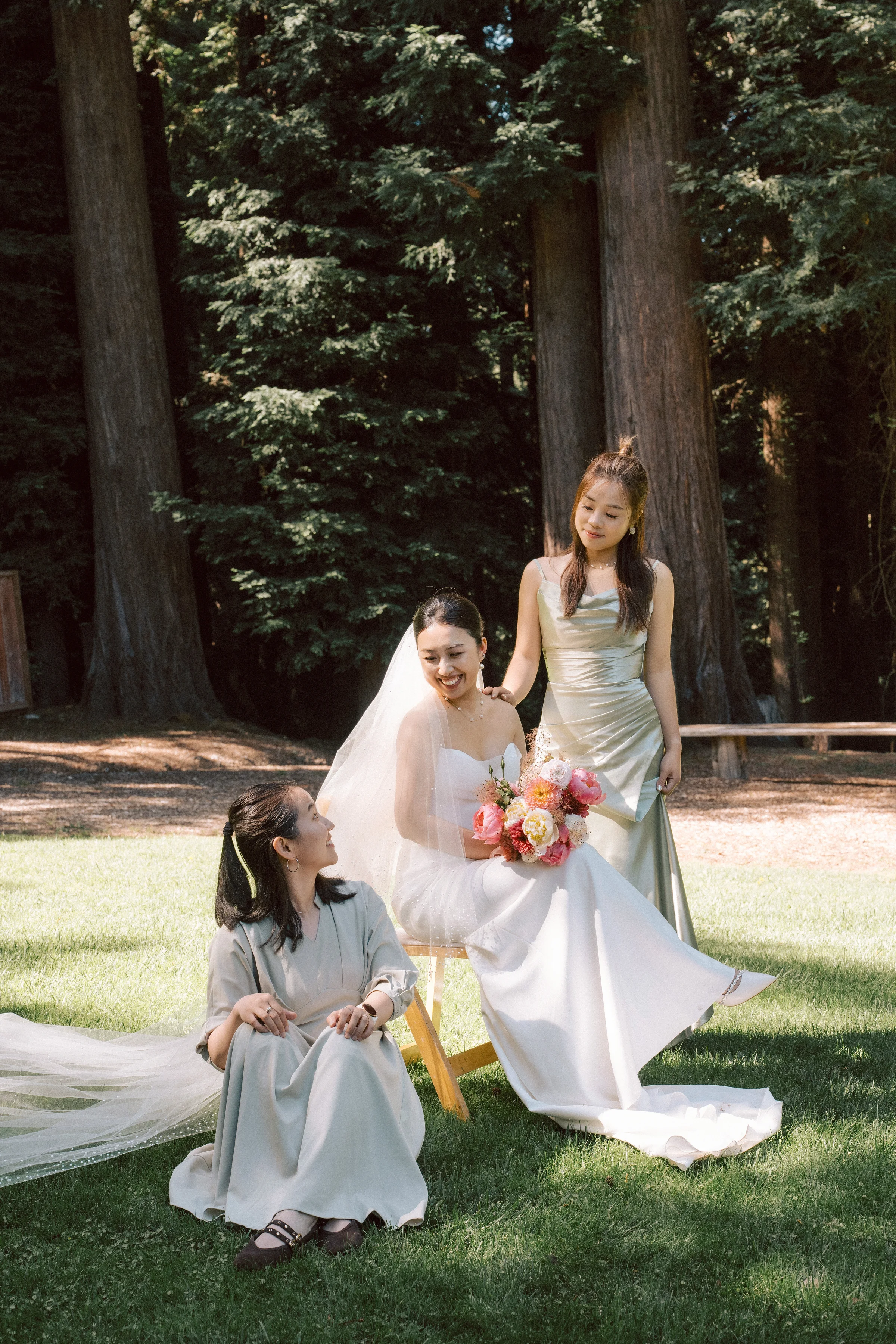 Bride crouching to greet a flower girl on the lawn