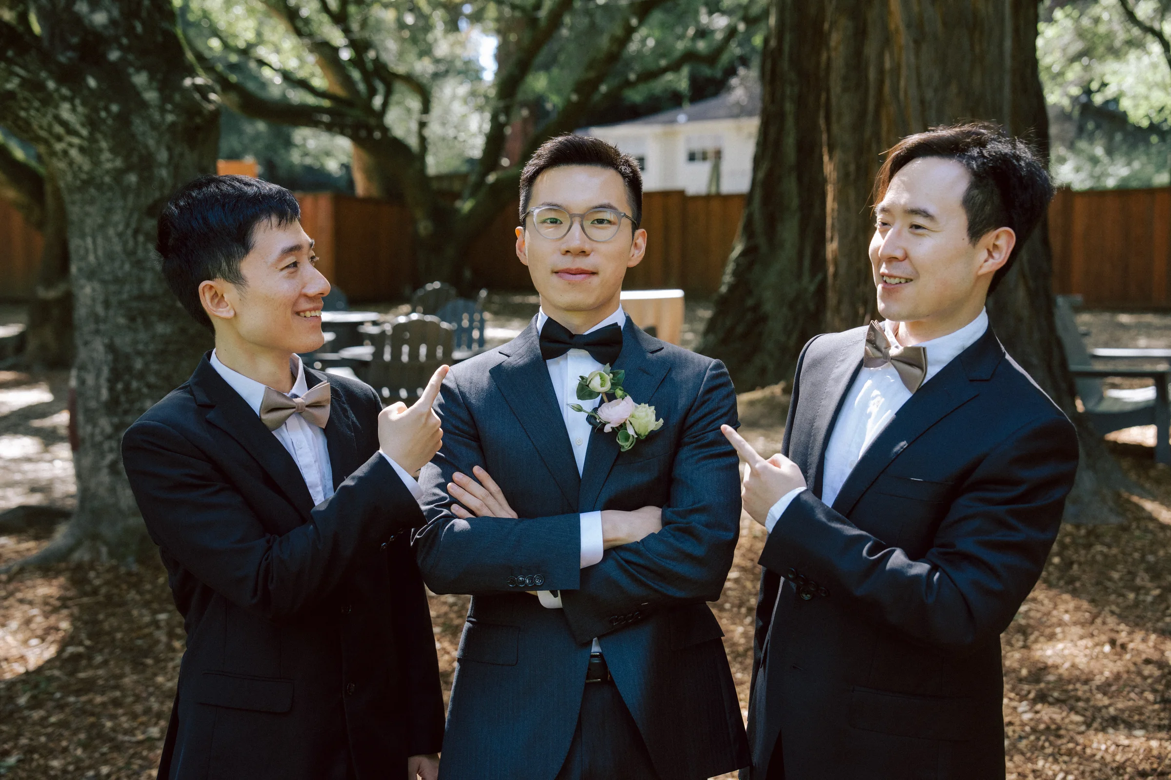 Groom flanked by two groomsmen in navy suits, arms crossed