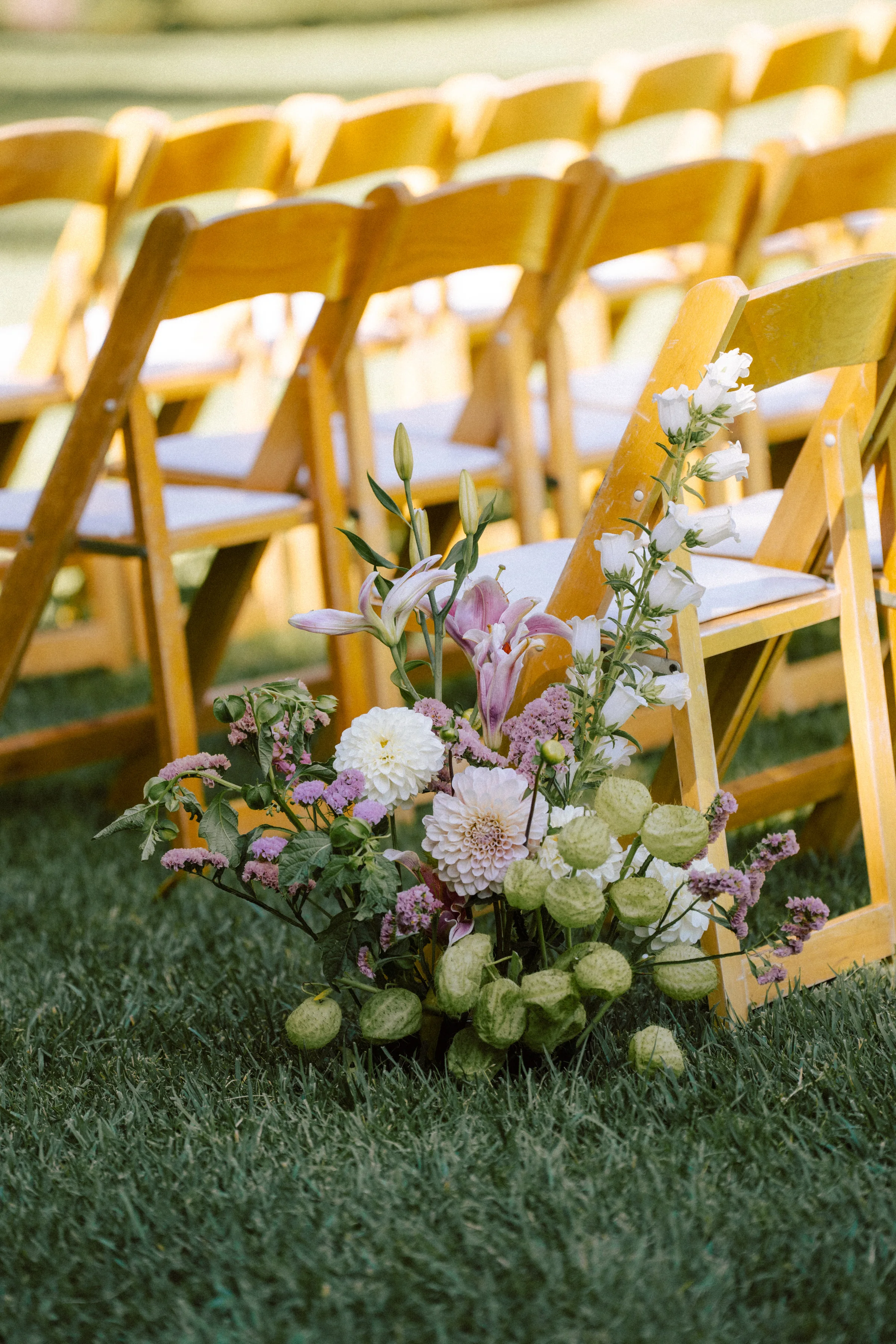 Aisle-end floral arrangement beside gold ceremony chairs