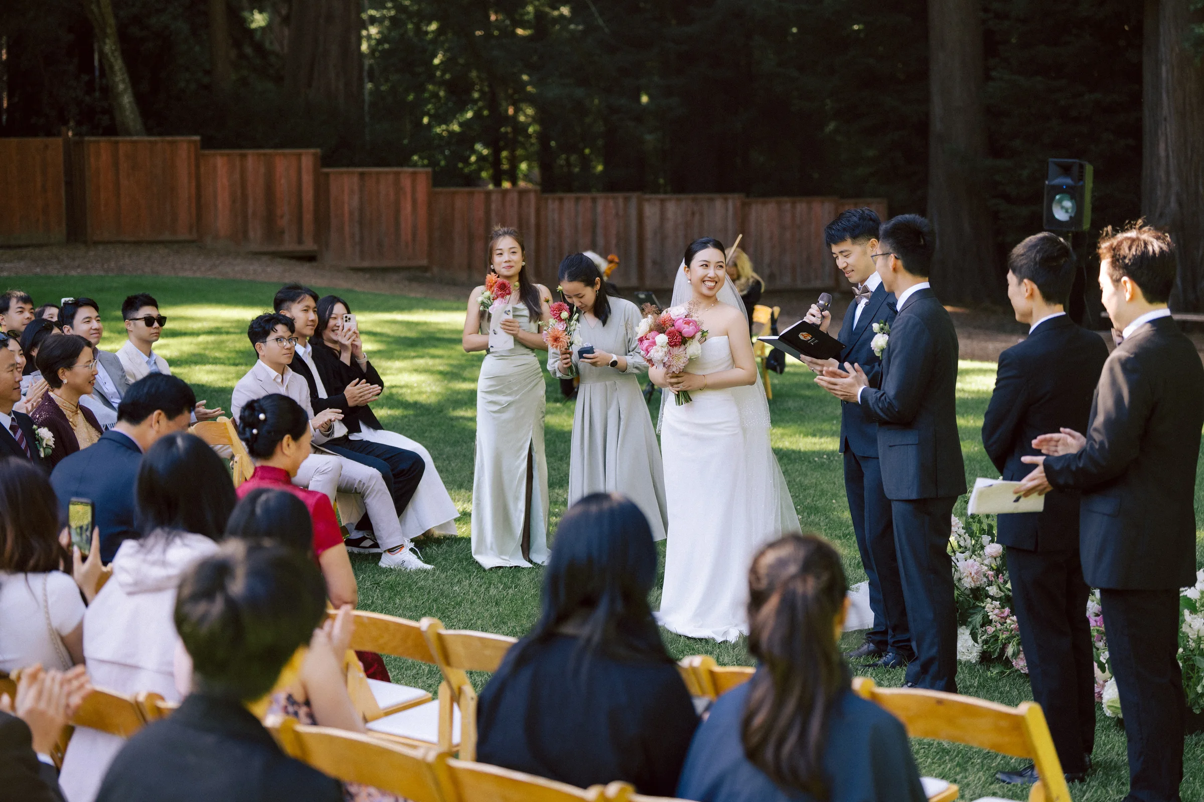 Wide view of the small ceremony set in a sunlit redwood clearing