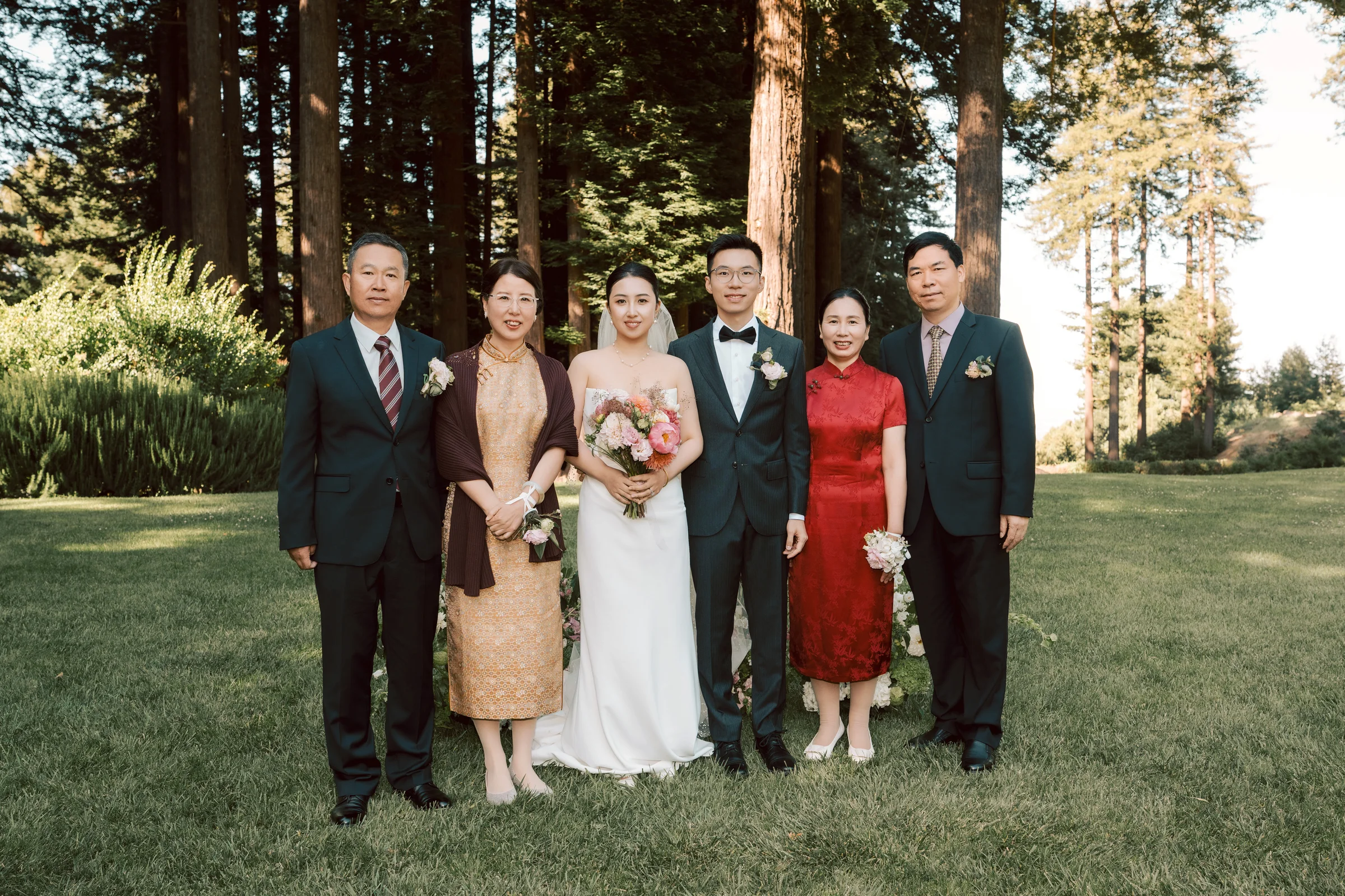Couple with four family members, two in traditional dress, holding a bouquet