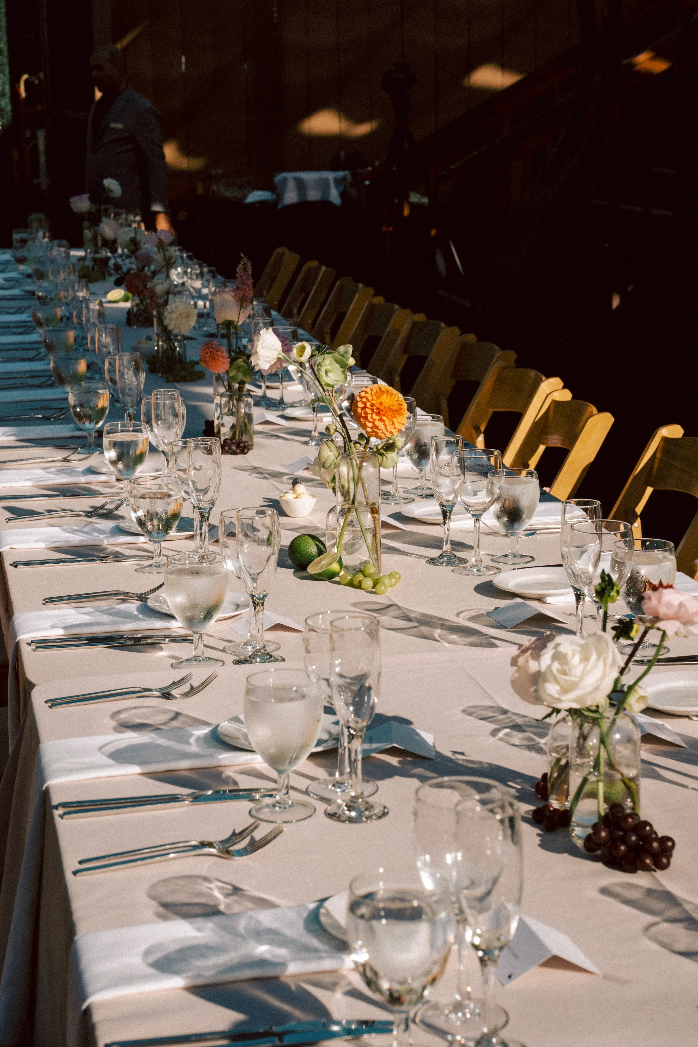 Long candlelit reception table with florals and gold chairs at night