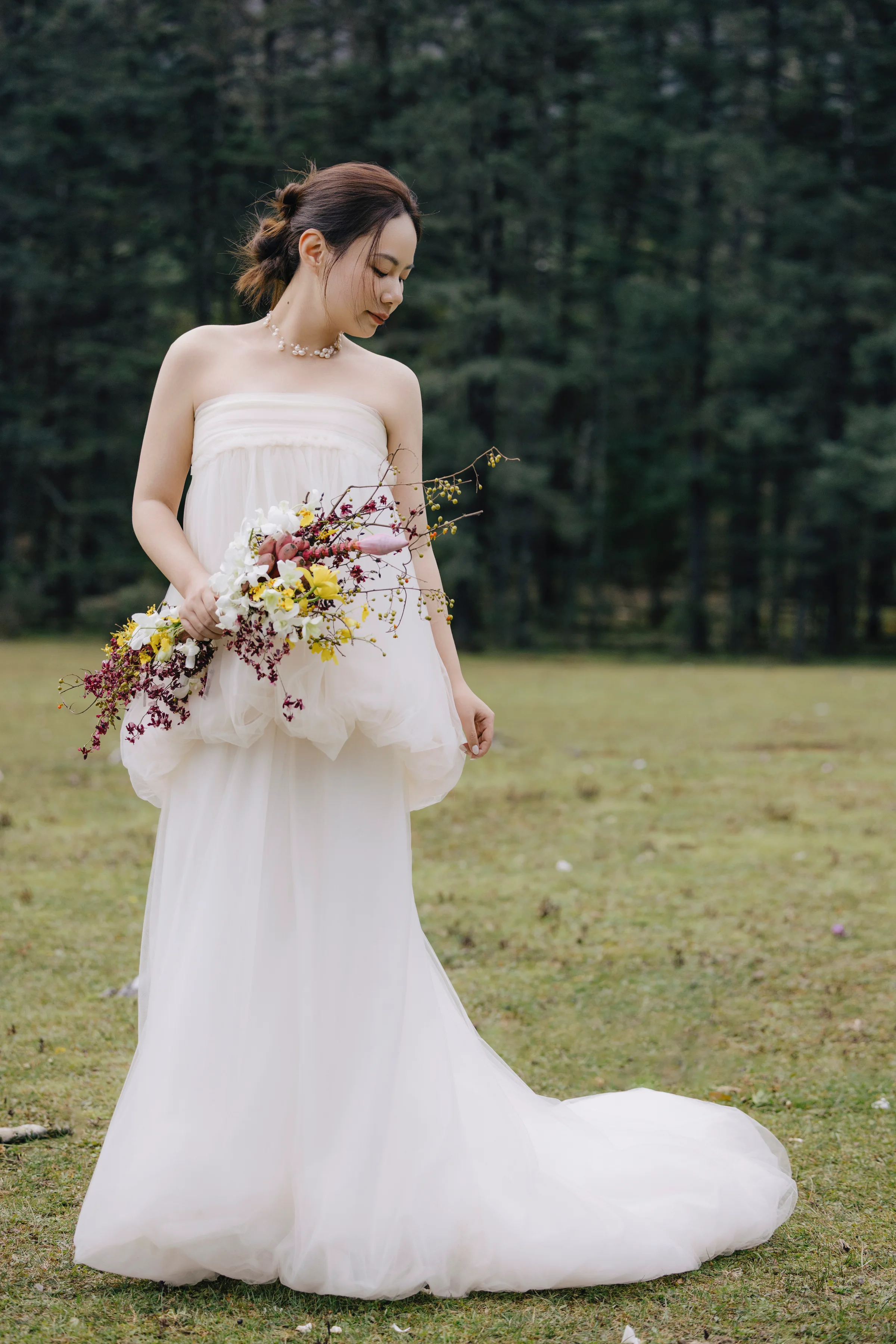 Bride in a strapless gown holding a textured bouquet in a mountain meadow