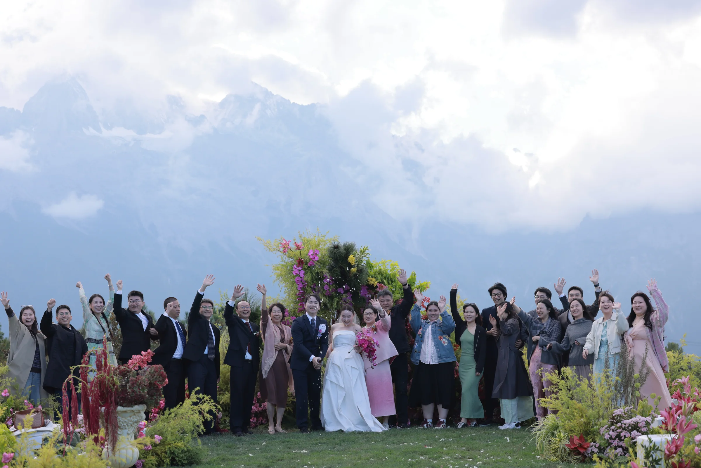 Wedding guests raising their arms in a group portrait with the mountains behind