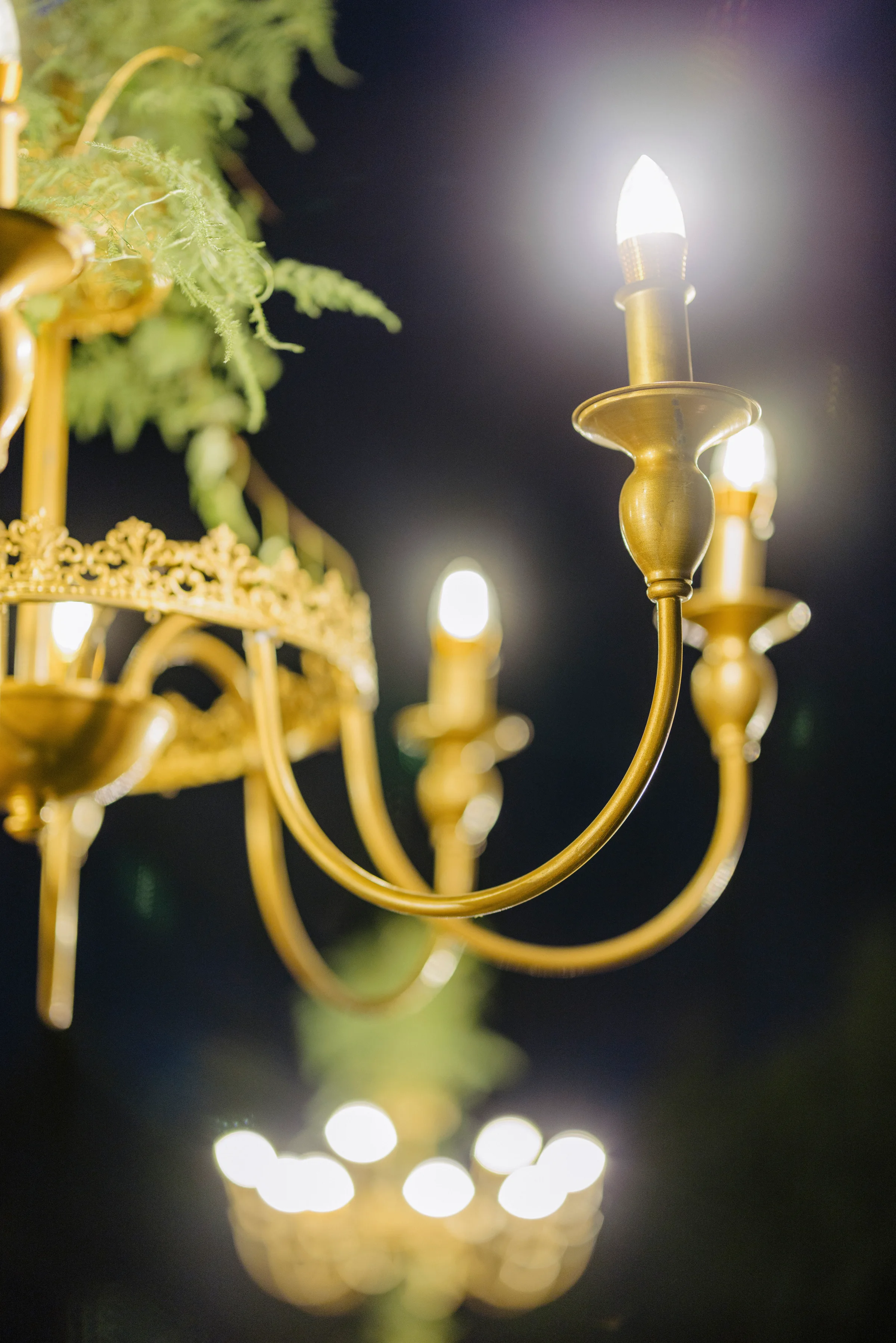 Gilded candelabra chandelier glowing at the evening reception