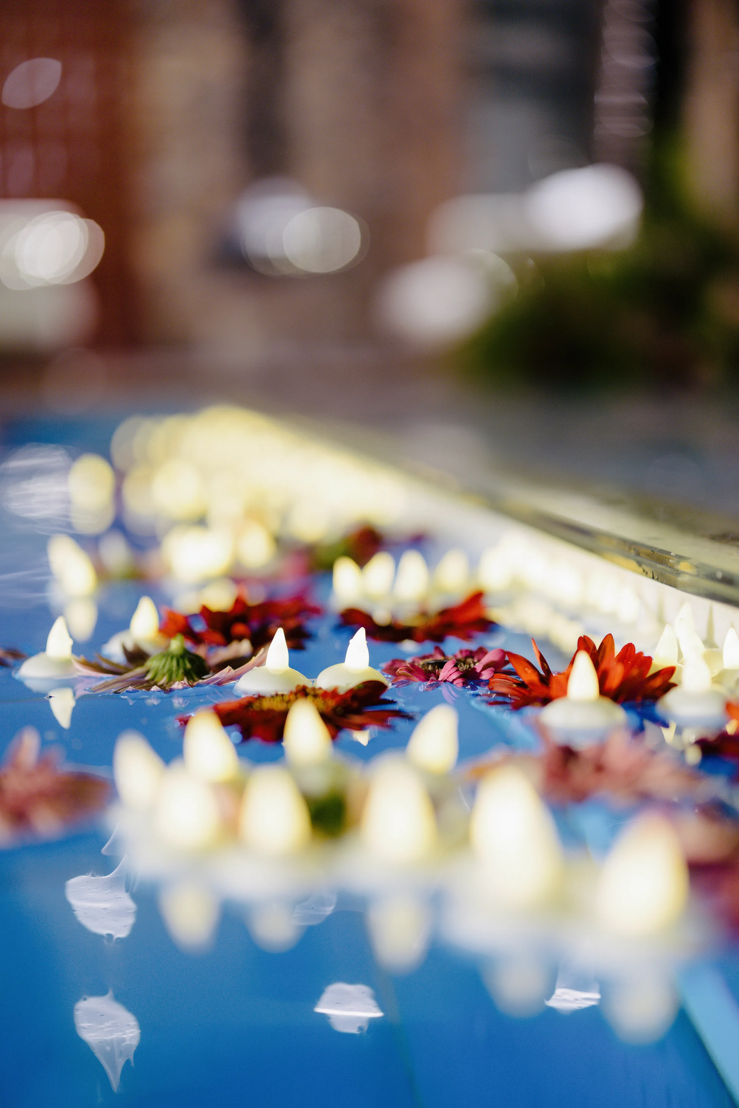 Floating candles and blossoms reflected on a dark water surface