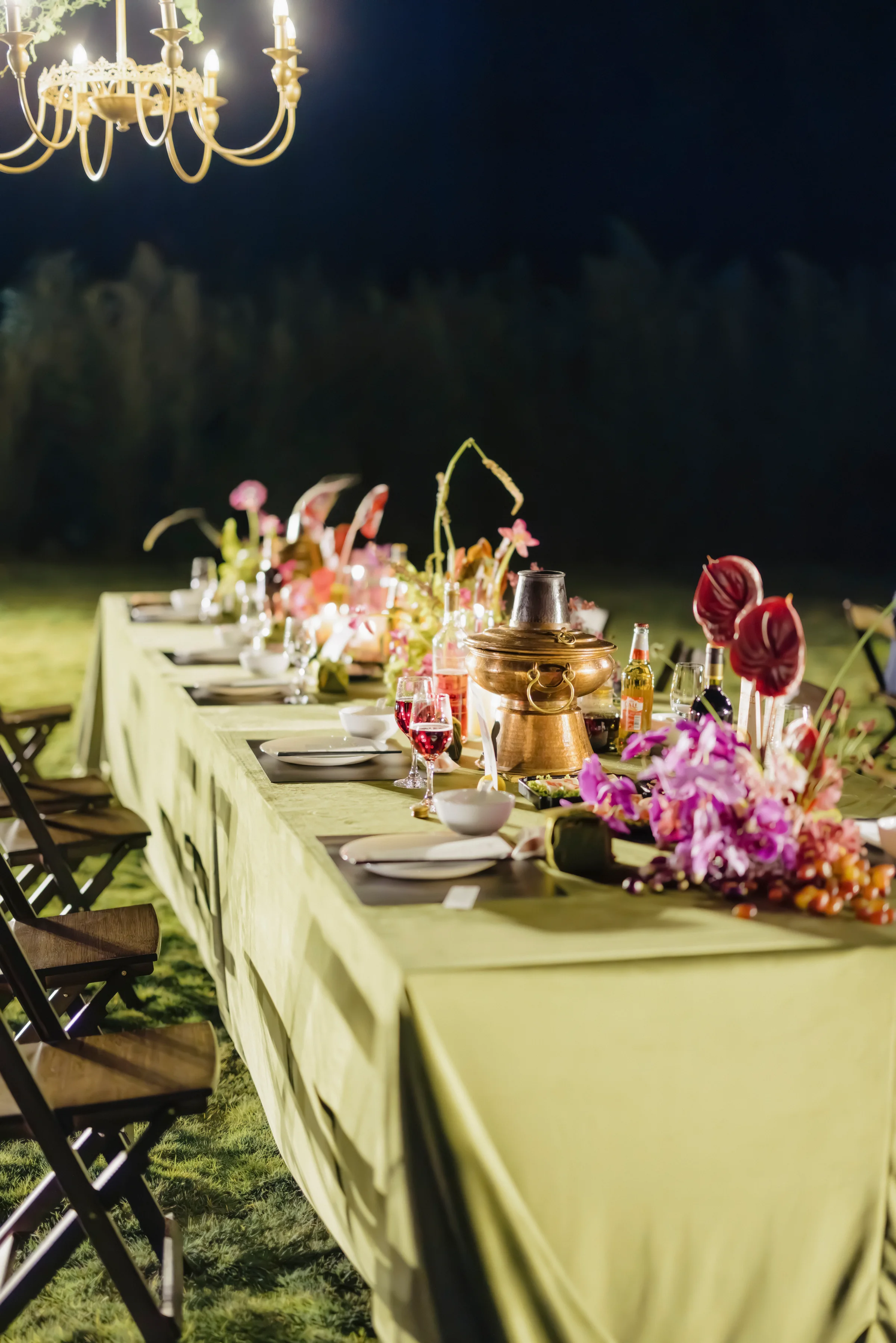 Long reception table with olive linen, candelabra, and florals at night