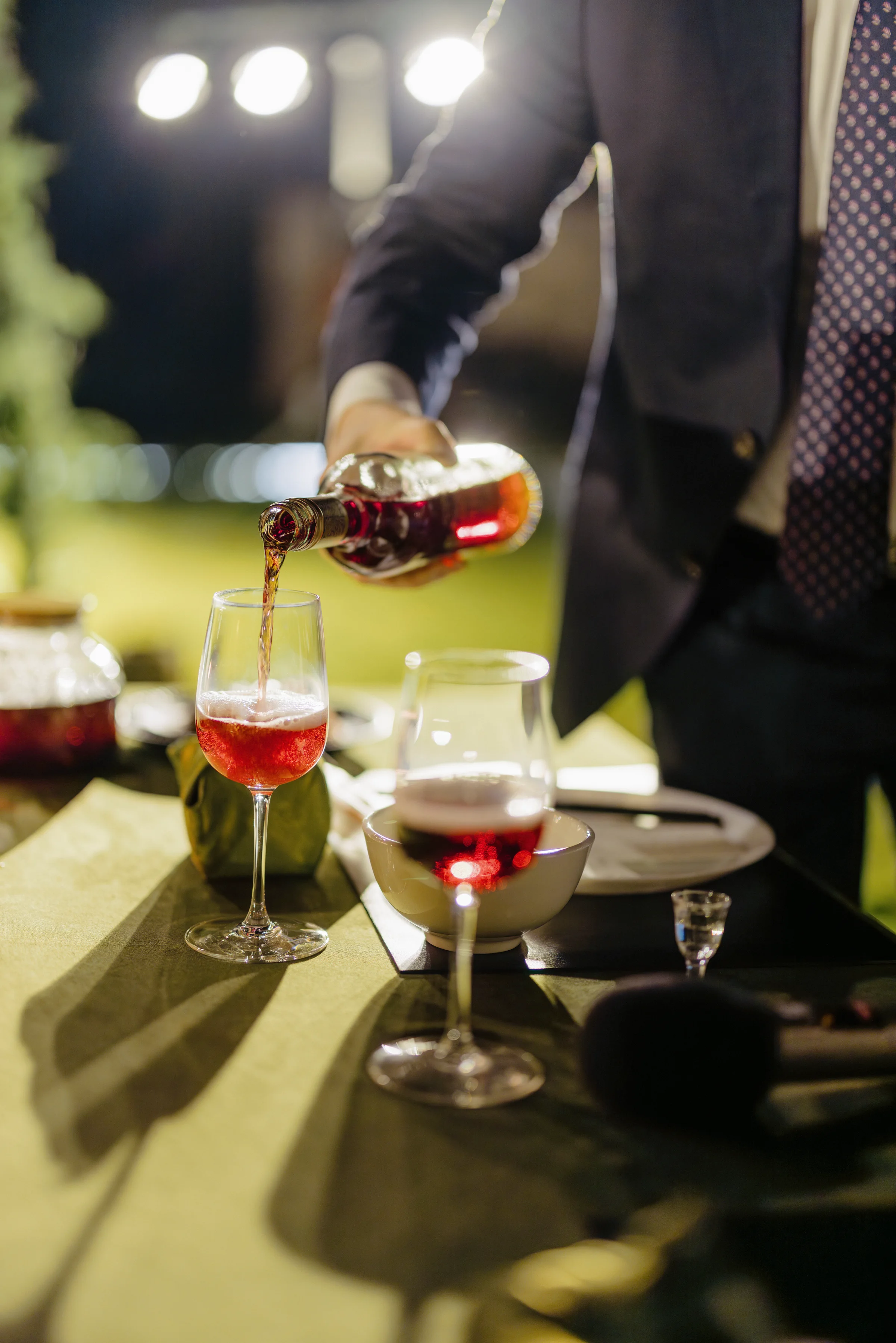 Red wine being poured at a candlelit place setting
