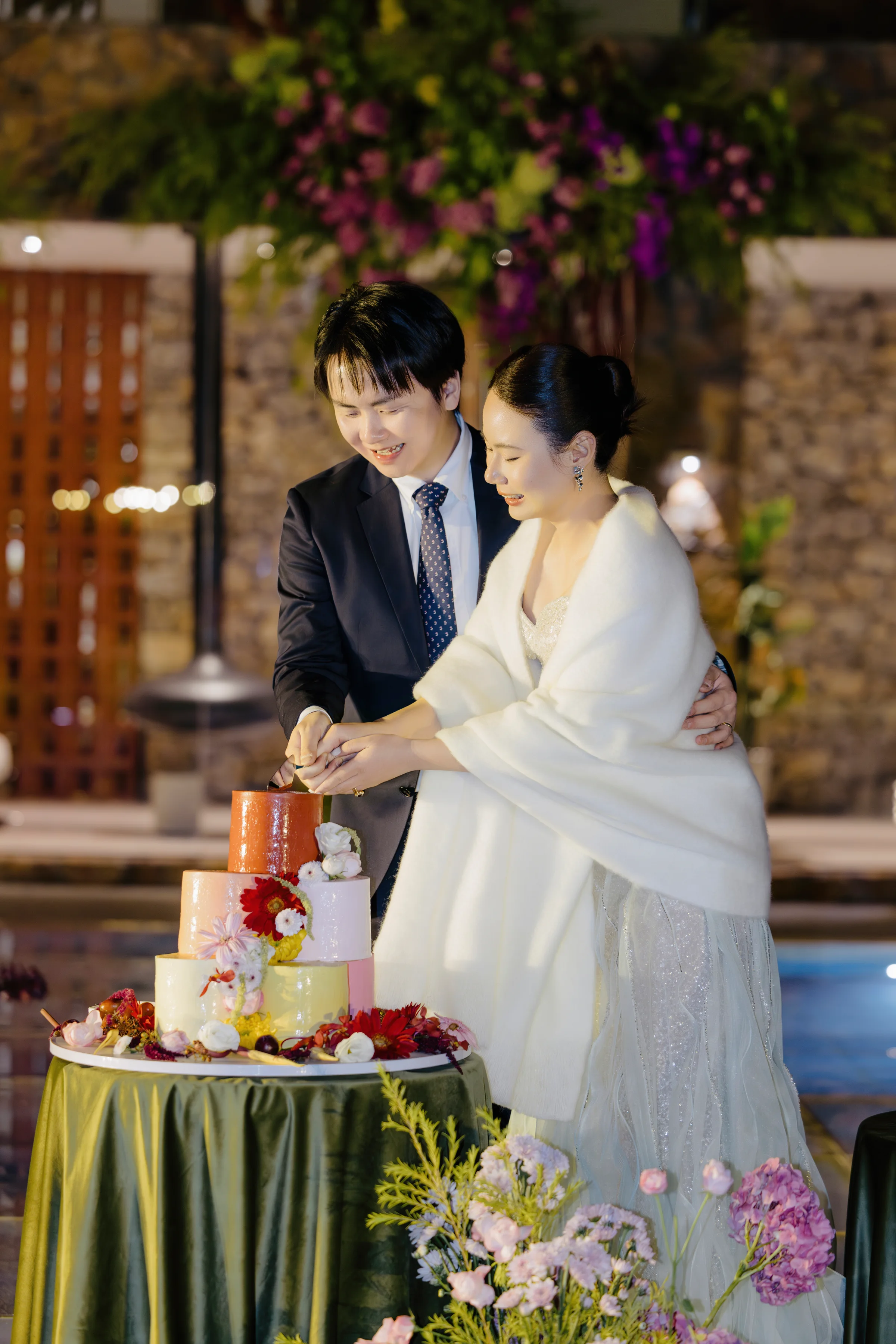 Couple cutting their cake, the bride in a white fur wrap