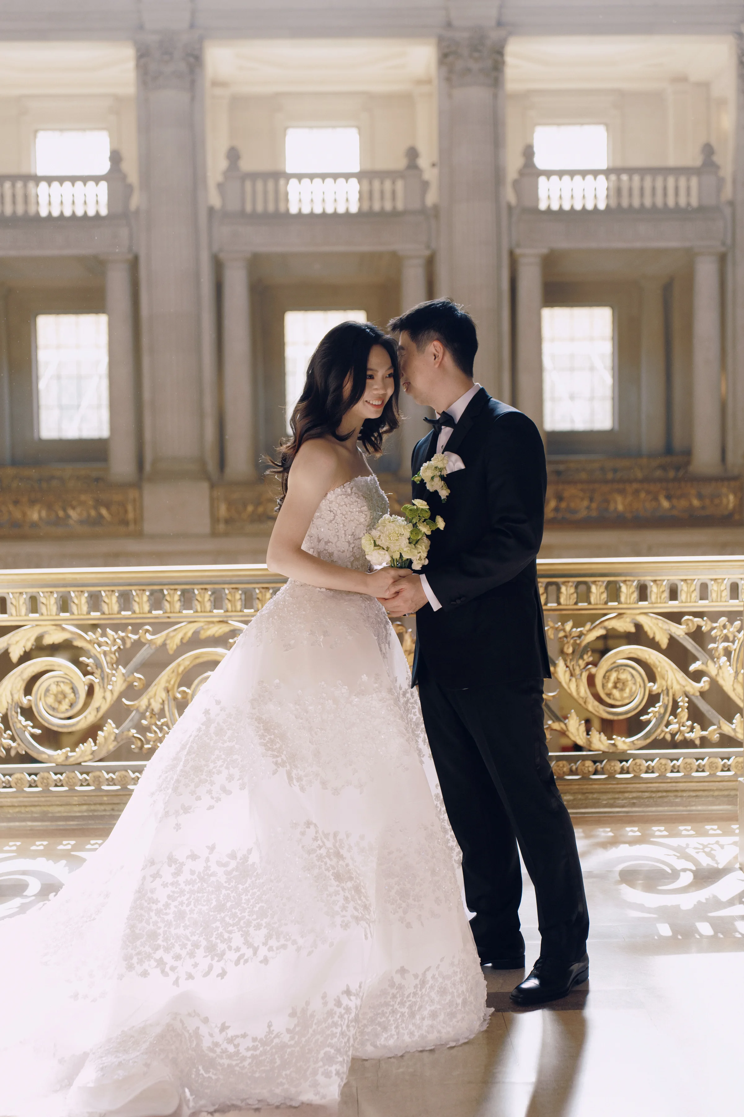Couple kissing on the marble staircase beneath the ornate gilded railing