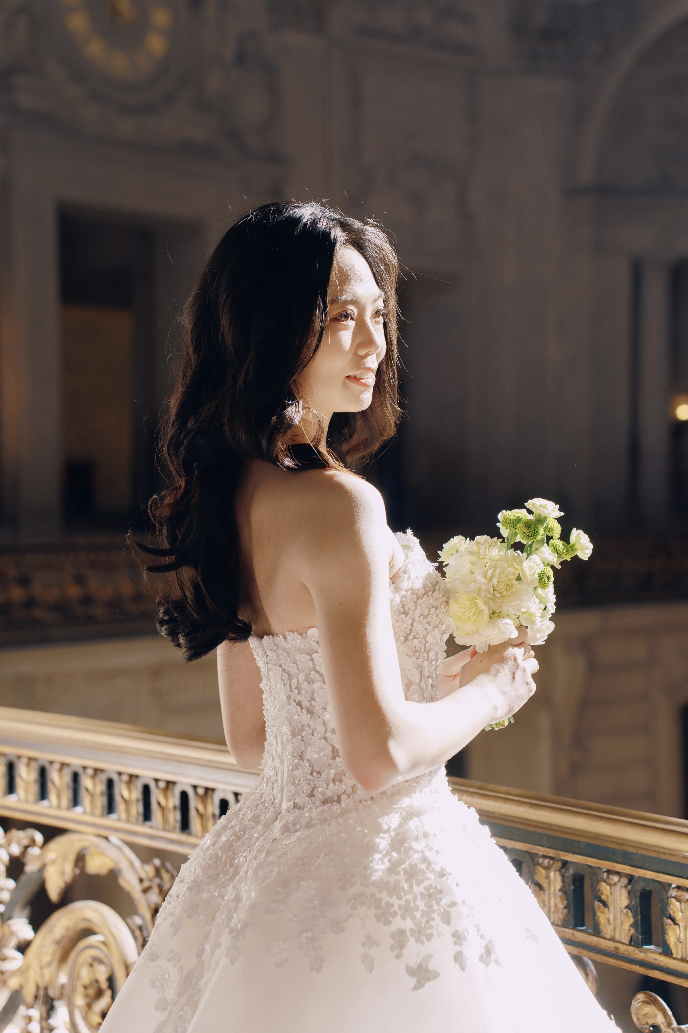 Bride holding her bouquet on the staircase, looking back over her shoulder