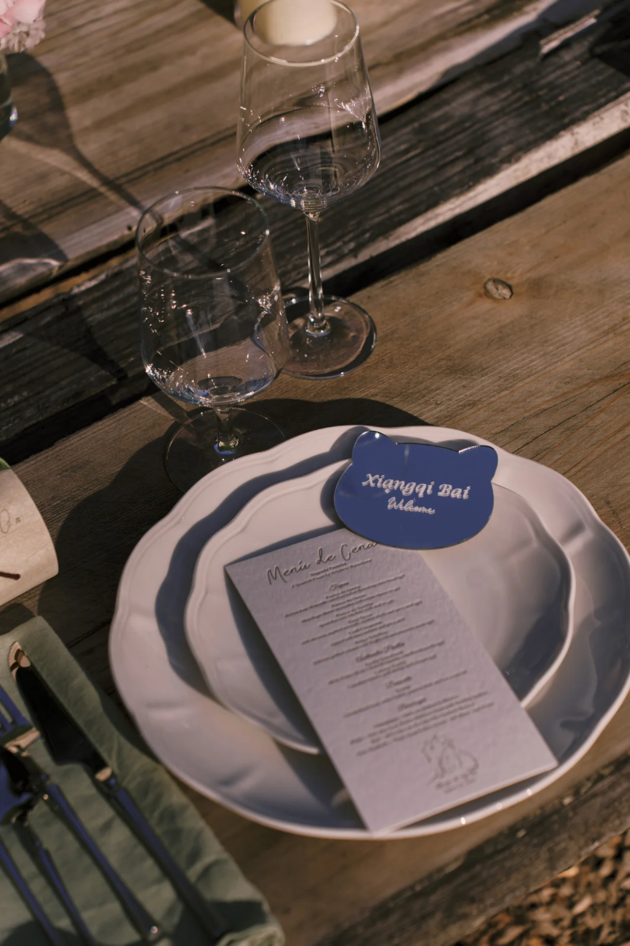 Blue butterfly place card and printed dinner menu arranged with white plates and glassware on a rustic table.