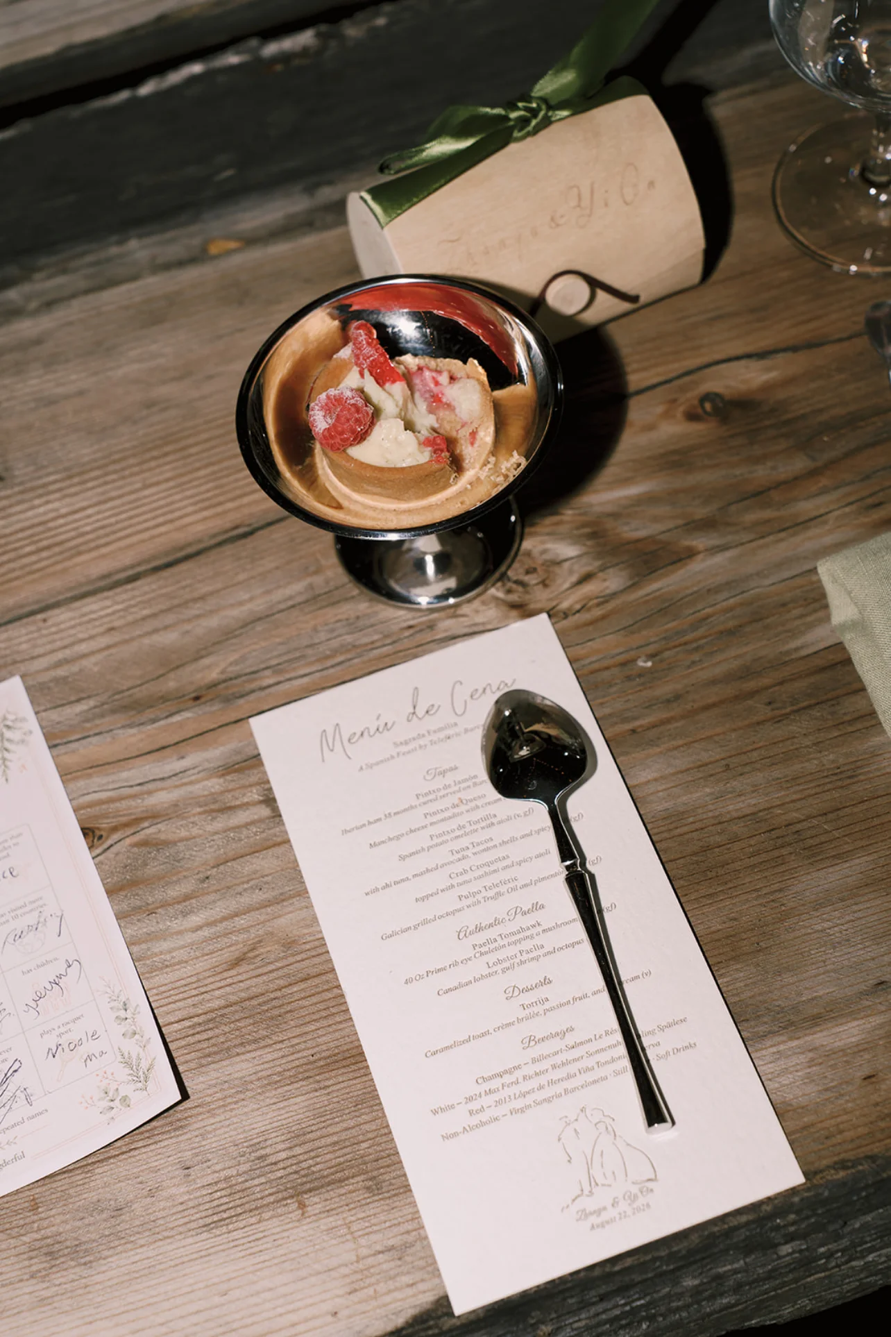 Raspberry dessert in a silver cup beside the reception menu and guest place setting.