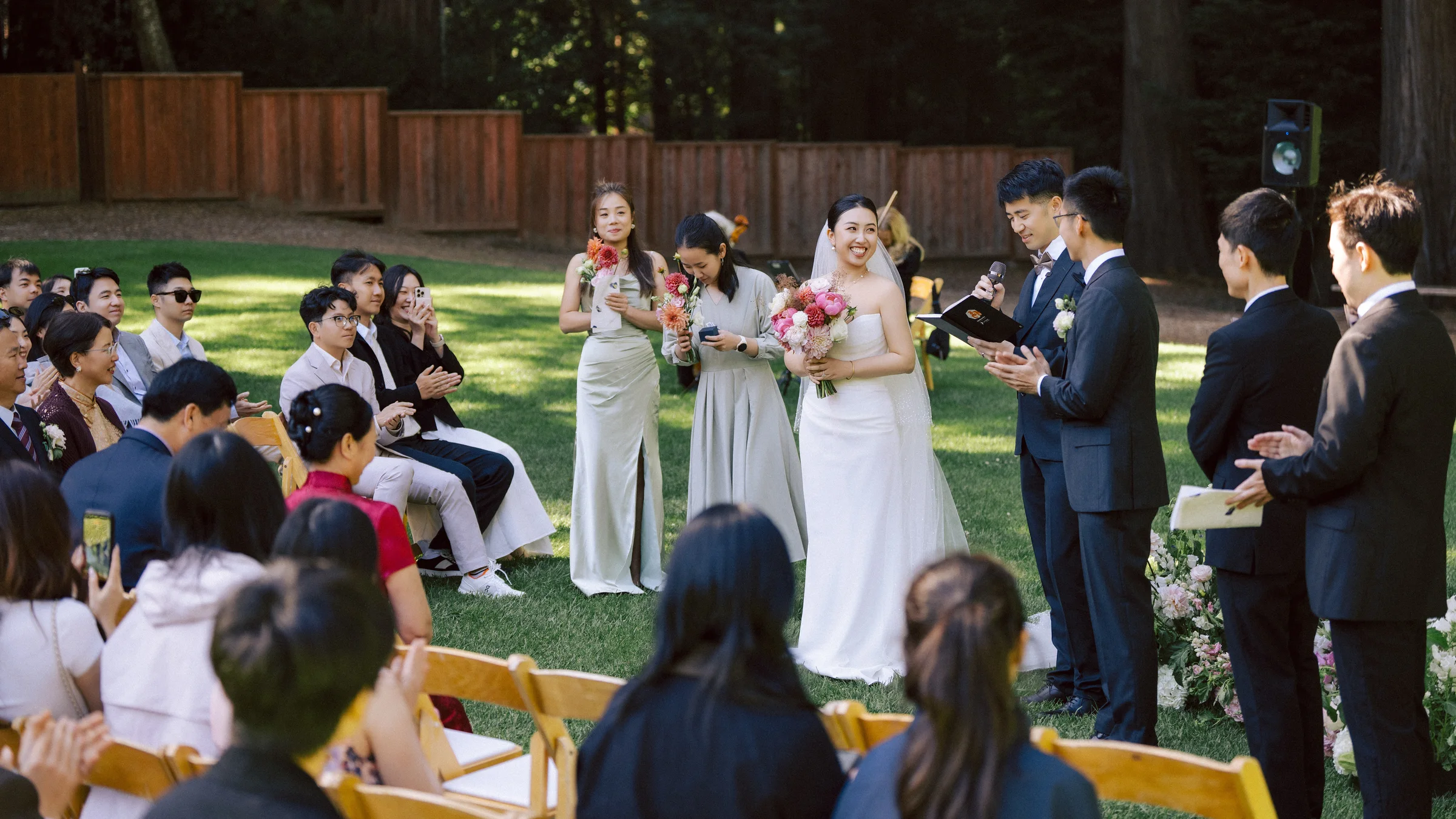 Bride and groom standing with their wedding party during an outdoor lawn ceremony