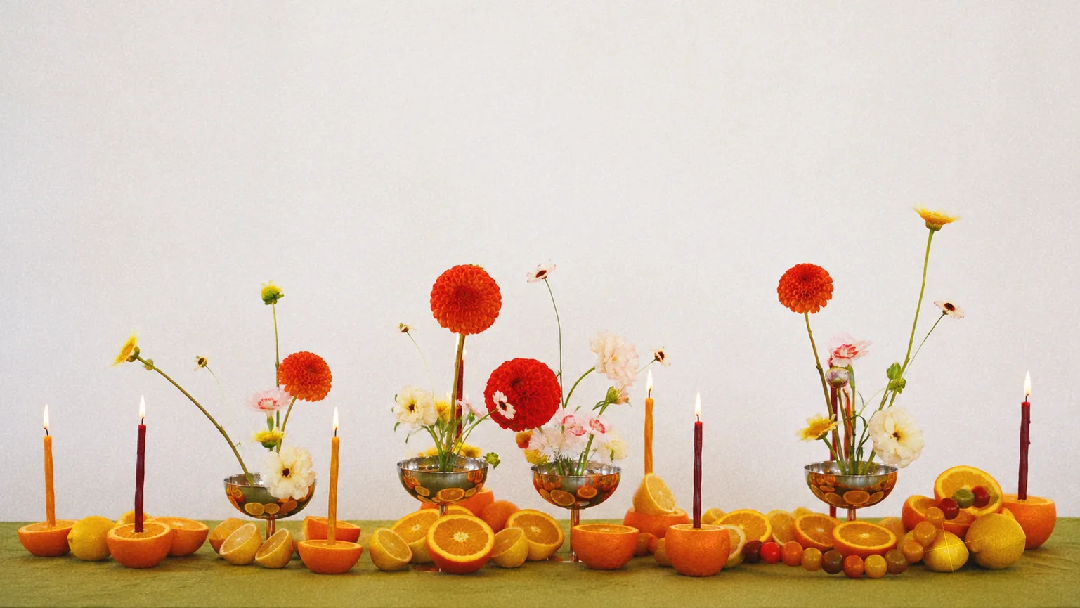 Orange-and-white floral tablescape styled with citrus fruit and taper candles